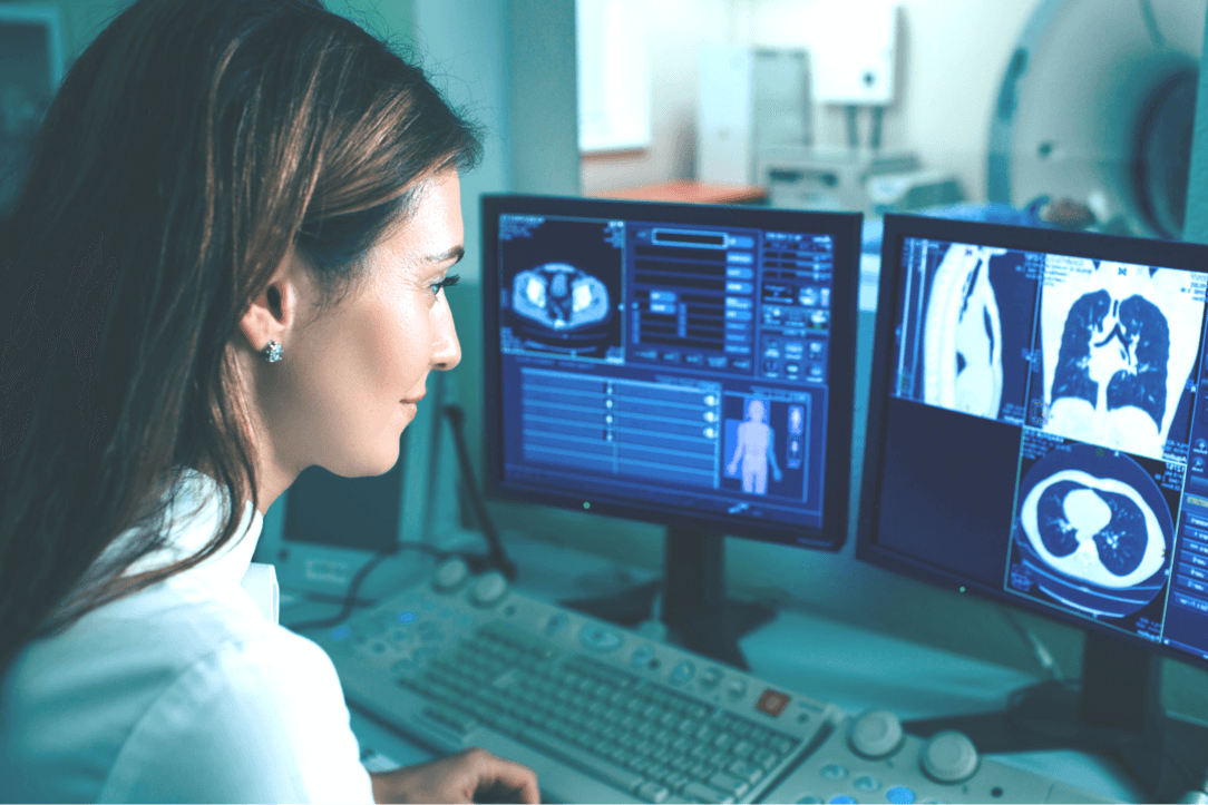 A woman analysing the results of a scan on two monitors